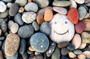 Stone with a painted smile to illustrate kindness.