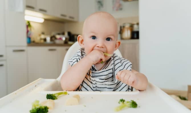A baby boy eats vegetables.