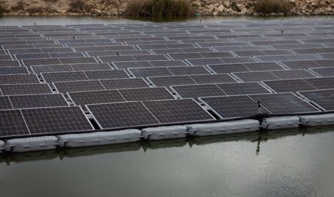 A solar panel system installed above a fish pond.