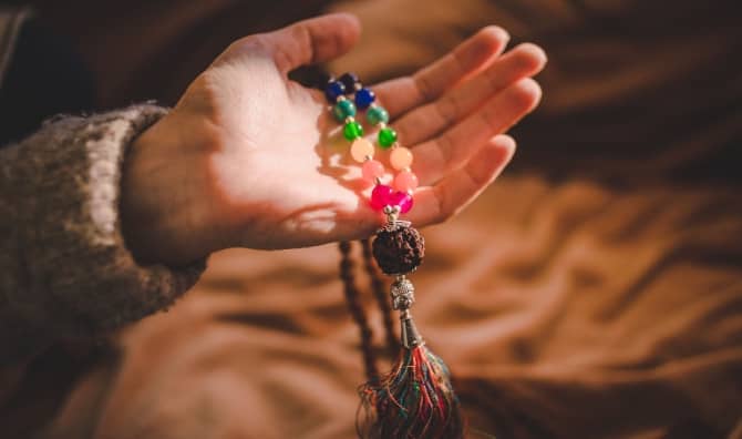Holding a mala bead necklace.