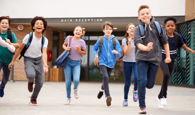 A group of students running out of a school building at the end of class.
