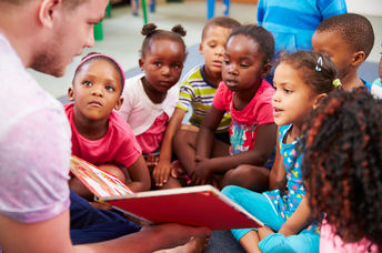 A volunteer reads a book to children. (Shutterstock)