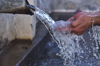 Clean water flows from a well into folded out hands