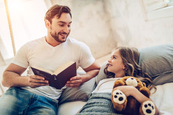 A father reads his daughter a bedtime story