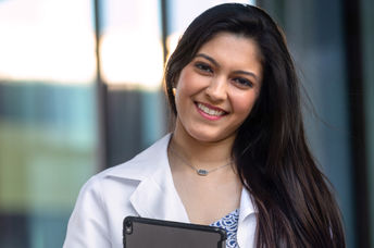 Native American student wearing a white hospital coat.