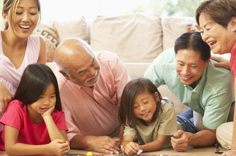 A family laughs while playing a board game.