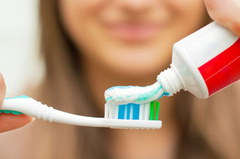 Woman putting toothpaste on a toothbrush.