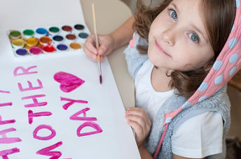 A young girl paints a Mother’s Day card.