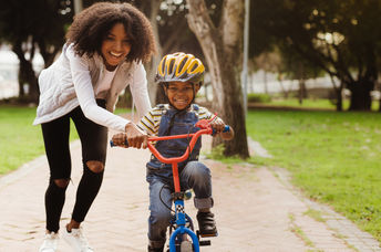 A mother teaching her child how to ride a bicycle.