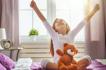 Young girl  happily waking up and stretching.