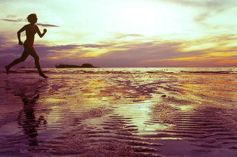 Healthy and mindful woman running on the beach.