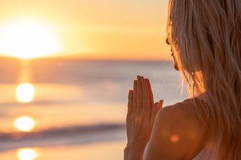 Girl meditating at sunset on beach