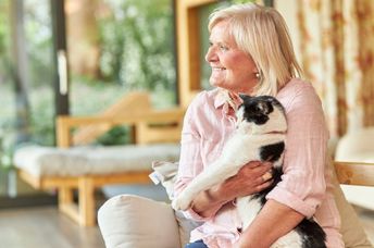 Senior woman cuddling a pet cat.