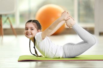 Girl doing yoga on a mat.