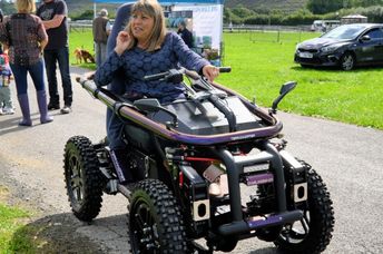 A woman using an all terrain motorized wheelchair.