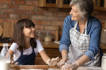 Grandmother teaching her granddaughter how to bake.