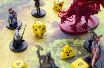 Playing Dungeons and Dragons on a board game map with a figure of a dragon, game characters and dice.