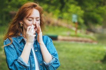 Woman using a nasal spray to relieve allergy symptoms.