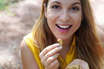 Young woman enjoying cashew nuts.