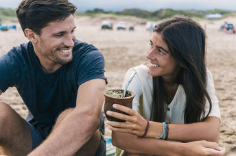 A couple sharing Yerba mate tea in a gourd.