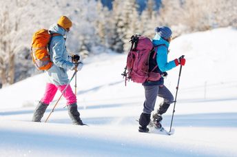 Two women winter hiking in snowshoes.