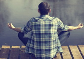 Man meditating by a pond