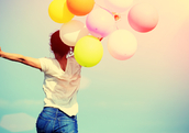 Happy woman jumping for joy with balloons