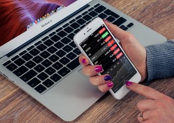 A woman checks a financial app on her iPhone