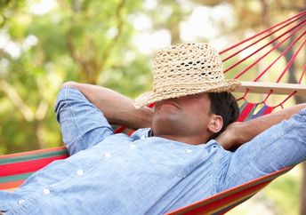 Man relaxing in hammock with hat covering his face