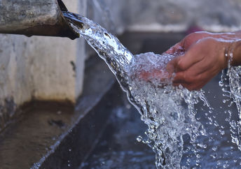 Clean water flows from a well into folded out hands