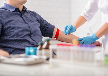 Close up of nurse disinfecting male arm before blood test. Man is sitting on chair near medical set