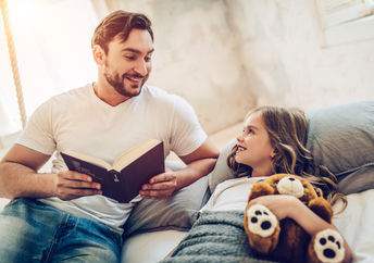 A father reads his daughter a bedtime story