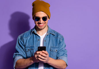 Smiling man on cellphone creates positivity using social media.