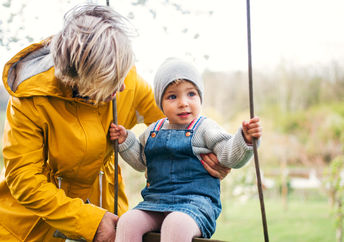 Grandmother helping a little kid on a swing