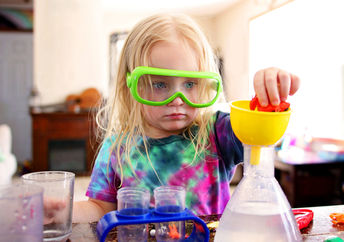 A little girl playing with a science toy.