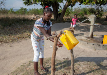 Girl washing her hands with a tippy tap.