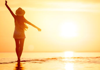 Woman walking on the beach at sunset.