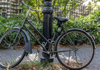 A bicycle chained to a post.