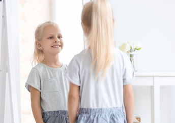 A little girl looking in the mirror.