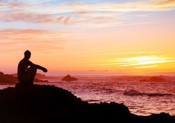 A woman sitting by the sea.