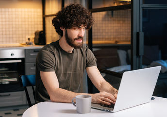 A young man typing on a laptop.