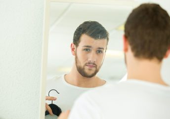 A man getting ready in front of the mirror. 