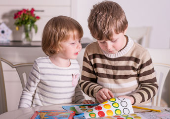 Two kids playing with stickers.