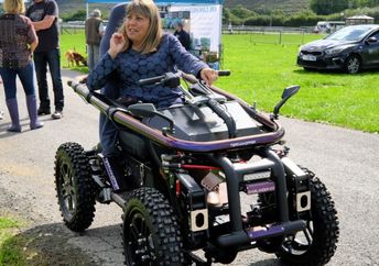 A woman using an all terrain motorized wheelchair.