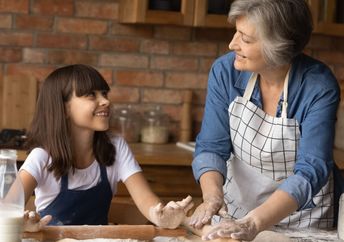 Grandmother teaching her granddaughter how to bake.