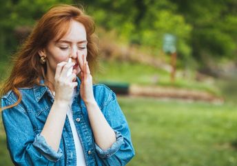 Woman using a nasal spray to relieve allergy symptoms.