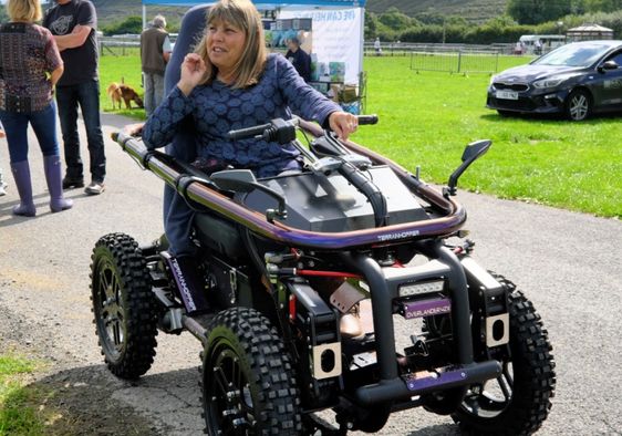 A woman using an all terrain motorized wheelchair.