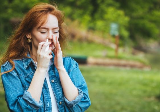 Woman using a nasal spray to relieve allergy symptoms.