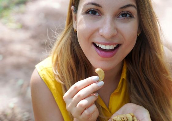 Young woman enjoying cashew nuts.