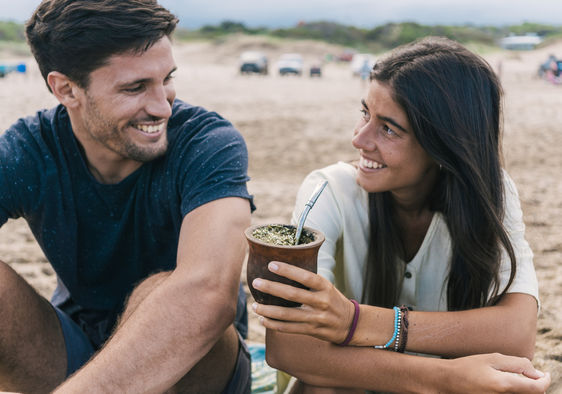 A couple sharing Yerba mate tea in a gourd.